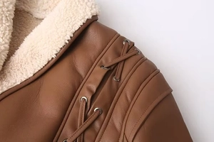 Détail de la veste en similicuir marron avec col en polaire crème et lacets aux épaules
