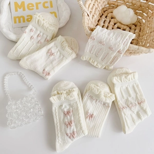 Close-up of white ruffle socks with pink bow details and delicate cotton texture