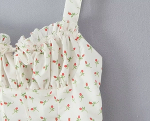 Detail of red floral print with ruffled neckline and delicate spaghetti straps on dress