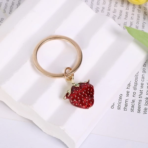 Detailed close-up of a 3D red strawberry enamel charm with a golden key ring holder