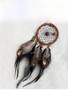Macro detail of handmade dream catcher car charm with brown feathers and beads