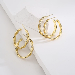 Close-up of golden twisted hoop earrings with clear and colorful zircon stones