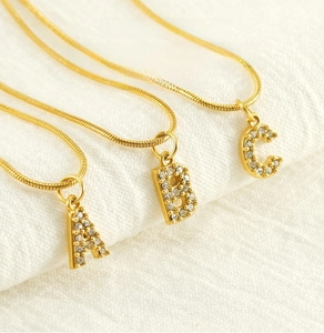 Detail of gold 18K plated stainless steel snake chain with crystal alphabet pendants