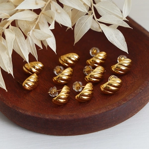 Gold-plated C-shaped twisted geometric stud earrings in a vintage wooden tray