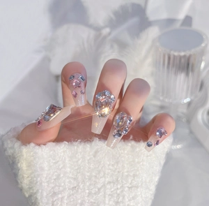 Detailed view of long almond press-on nails with luxury pink rhinestones and diamonds