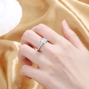 Detailed view of a six-prong sparkling zircon ring worn on a finger with silk background