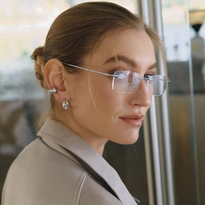 Elegant silver stainless steel hoop earrings and frameless glasses worn by a model