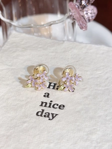 Detail of purple enamel flower earrings with gold stamens on a white jewelry card