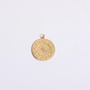 Detailed view of a gold-plated zodiac pendant with starburst engraving and metal texture