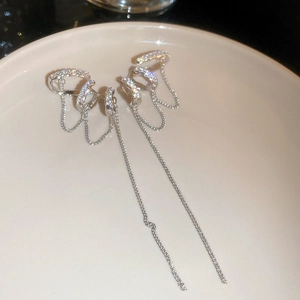 Détail de clips d'oreilles à franges argentées et zircons sur un plateau en céramique