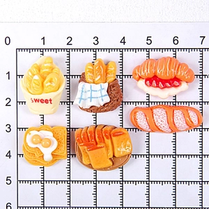 Detailed view of six miniature resin bread and snack models with measurement scale grid