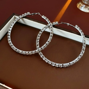 Close-up of luxury silver hoop earrings with sparkling rhinestones on a jewelry tray