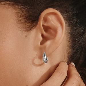 Close-up of a silver C-shaped earring with micro-set zircons worn by a model