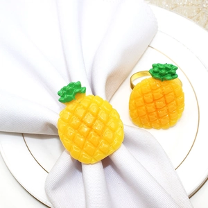 Detail of yellow pineapple napkin rings with golden bands on a white plate