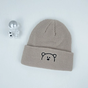 Detailed embroidery of a cute black bear on an oatmeal knitted ribbed beanie for kids
