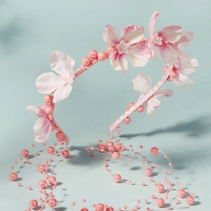 Detail of pink fabric flowers and beaded tassels on an elegant bridal headband
