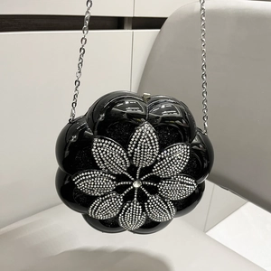 Close-up of a flower shaped black evening bag with silver rhinestone petals and chain