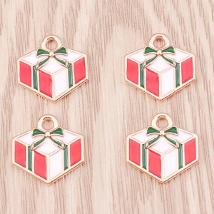 Close-up of enamel Christmas gift box pendants with golden edges on wood background