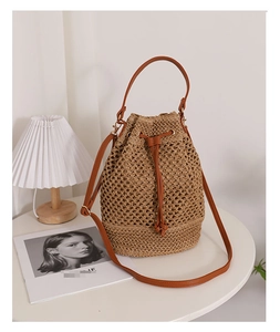 Detailed view of hollow straw bucket bag with brown leather drawstring closure and strap