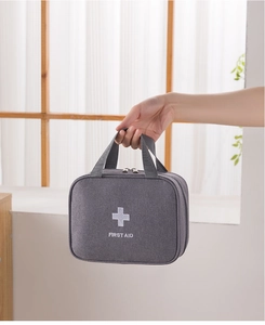 Close-up of portable grey first aid kit bag with white cross and handle on a bright windowsill
