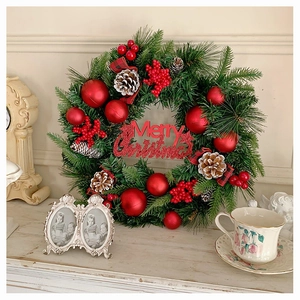 Detail eines Weihnachtskranzes mit roten Beeren, Zapfen und Merry Christmas Schild