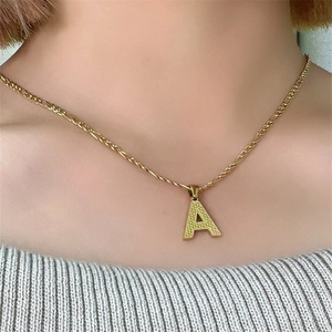 Collana in acciaio al titanio dorato con ciondolo lettera A e catena a corda su modella