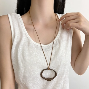 Detail of adjustable long brown leather cord necklace with irregular geometric pendant