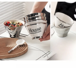 Close-up of stackable ceramic bowls with silver electroplated rims and modern typography