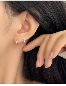 Detail shot of gold and silver hoop earrings with cubic zirconia on a female ear