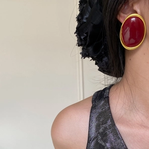 Close-up of vintage oval red stud earring with gold border worn by a model