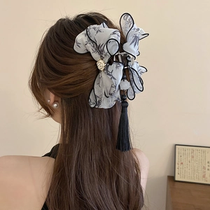 Détail de pince à cheveux avec nœud en bambou, rose en métal et longs glands en soie