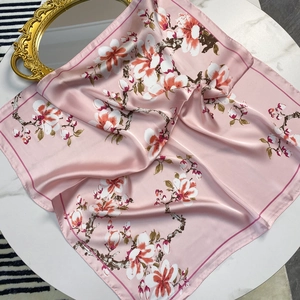 Detail of pink floral silk scarf with glossy satin finish and elegant flower pattern