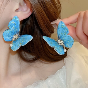 Detailed view of elegant blue butterfly earring with gold foil, crystal and pearl drop