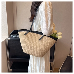 Detail of woven straw tote bag featuring black shoulder straps and tulip decoration