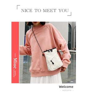 Detail of off-white nylon crossbody bag with orange drawstring and woven strap