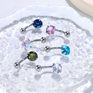 Macro view of assorted zircon belly rings in multiple colors on a textured glass tray