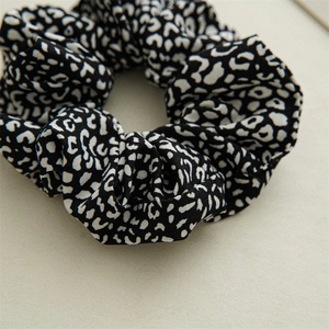 Close-up of black and white leopard print fabric scrunchie on beige background