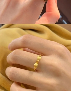 Detail of a 18K gold plated bow ring showing brushed texture on a warm velvet background