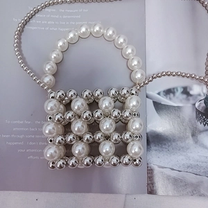 Detail of handcrafted silver beads and white pearls on a mini crossbody handbag