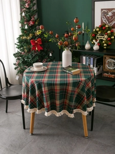 Detail of round red and green plaid tablecloth with decorative beige fringe tassels