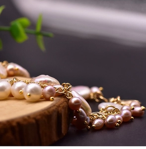 Macro shot of natural baroque pearls with gold links displayed on a rustic wood slice