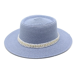 Detail of light blue straw hat featuring delicate white lace trim and pearl embellishments