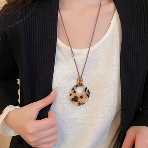 Detail of tortoise shell resin ring pendant with orange bead on long brown cord
