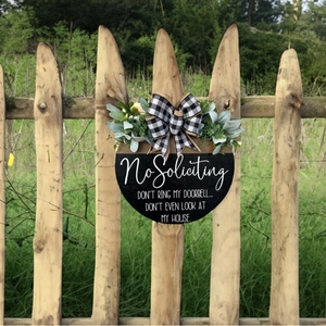 Round wooden No Soliciting front door sign with buffalo plaid bow and greenery decor
