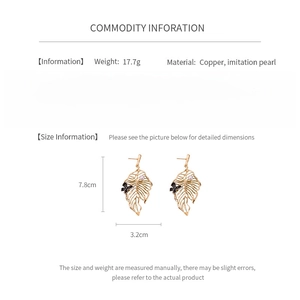 Detailed view of gold leaf earrings with pearl and butterfly accents, 7.8cm length