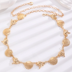 Detail of gold metal waist chain with polished seashell and conch links on white surface