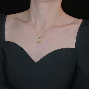Gros plan d'un collier carré doré en pierre œil de chat sur un mannequin sur fond noir