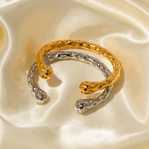 Detailed view of hammered texture on gold and silver stainless steel open bangles