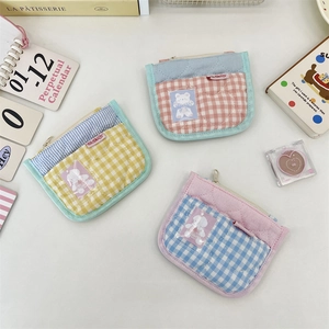 Close-up of quilted plaid coin purses with heart stitching and cute cartoon patches