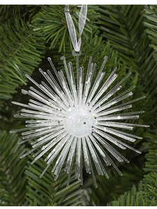 Close-up of sparkling white star ornament hanging on green Christmas tree branch